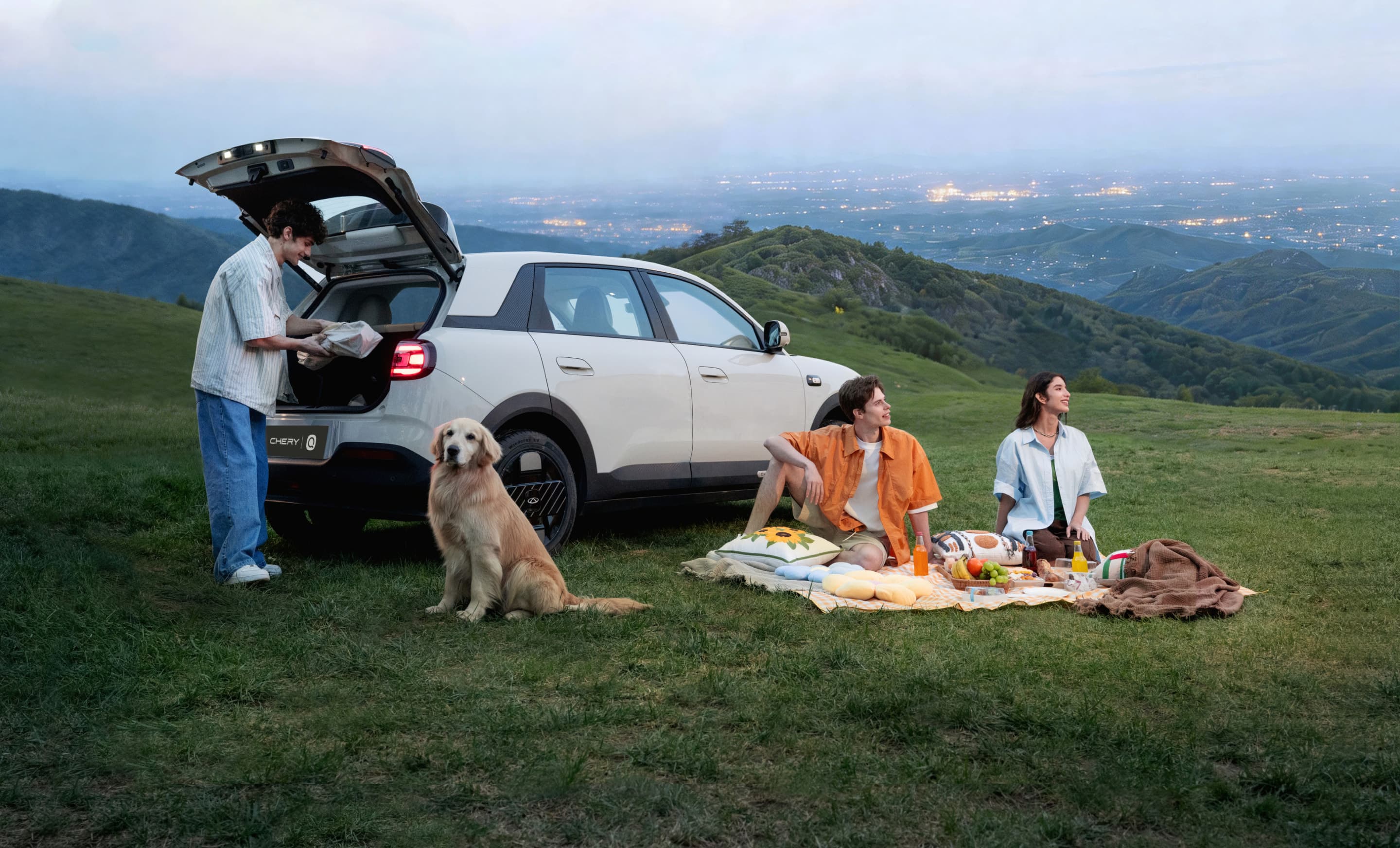 Chery Q parked on a hillside with a picnic at twilight